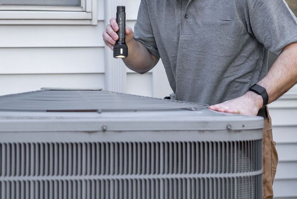 A technician inspects an outdoor HVAC unit for maintenance.